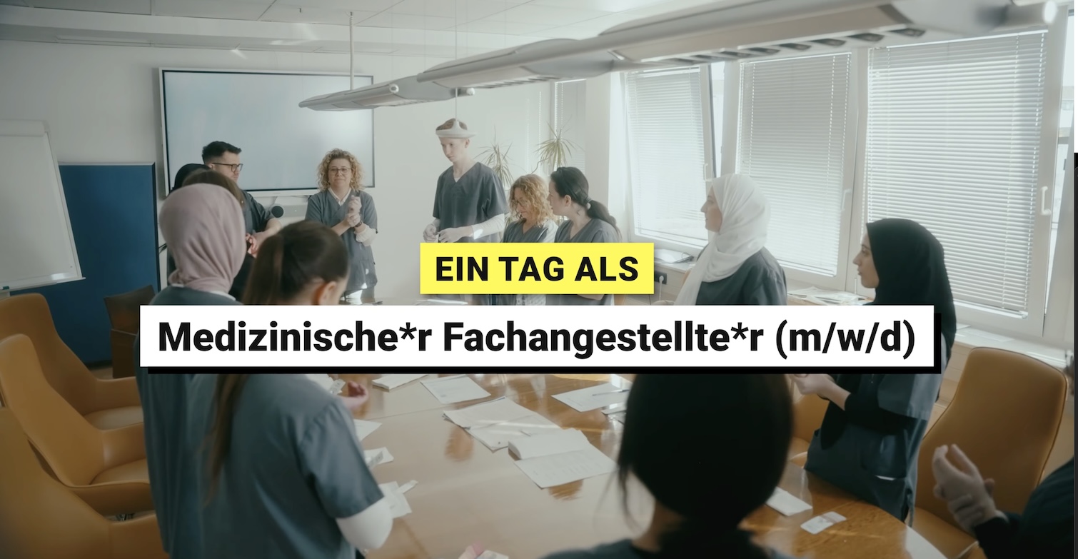 Vorschaubild des Videos zeigt mehrere Personen um einen langen weißen Konferenztisch