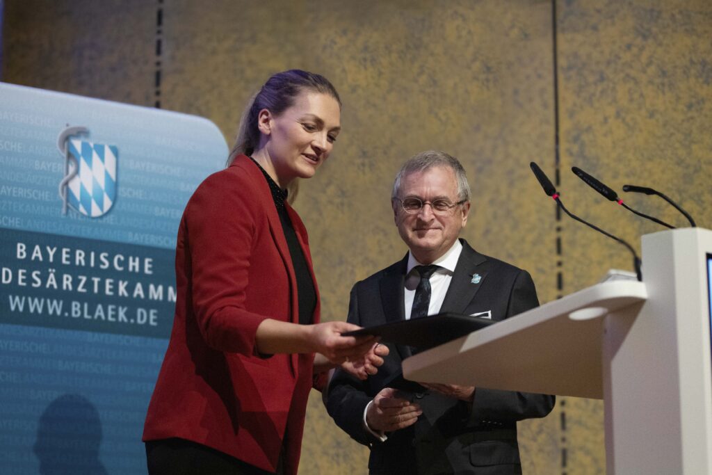 Judith Gerlach, Baye­ri­sche Staats­mi­nis­te­rin für Gesund­heit, Pflege und Präven­tion, über­reicht Dr. Gerald Quit­te­rer, Präsi­dent der BLÄK, das Verdienst­kreuz am Bande des Verdienst­or­dens der Bundes­re­pu­blik Deut­sch­land